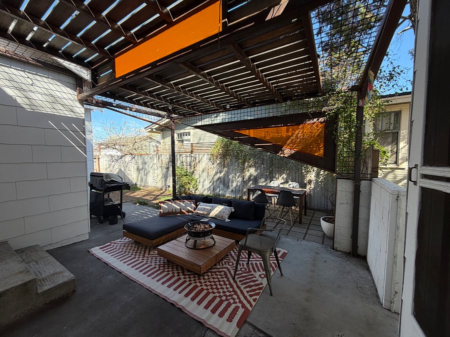 Fenced in backyard with pergola, patio set, fire pit, bbq, dining area, grass, shade, and plants. Access to the side yard, garage, and RV pad.