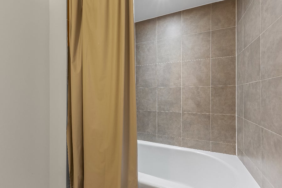 Enjoy a quiet soak in the full-size tub, finished with elegant floor-to-ceiling tiling for a polished, modern look.
