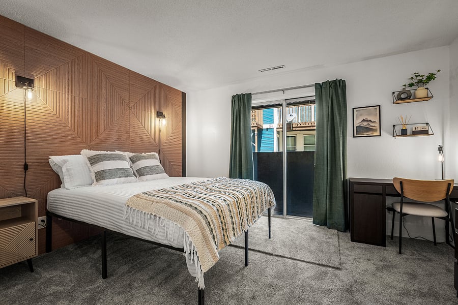 Bedroom with queen bed, dedicated work station, several storage options, natural lighting, blackout curtains