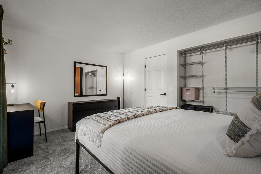 Bedroom with queen bed, dedicated work station, several storage options, natural lighting, blackout curtains
