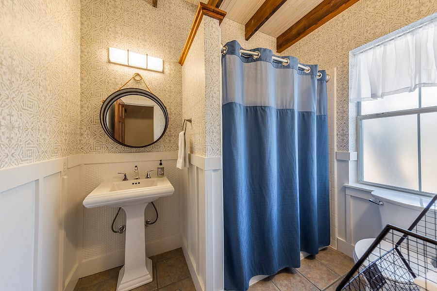 The second bathroom is located on the first floor next to the laundry room. It features a full-size tub with a shower and a pedestal sink.