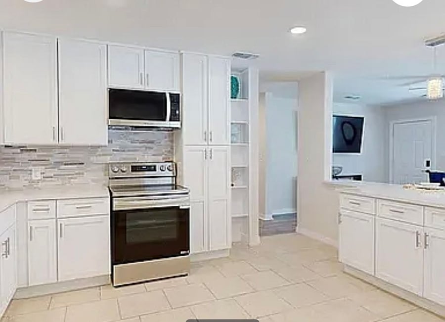 Open kitchen layout with built-in shelving, pantry storage, and clear sight lines to the living area