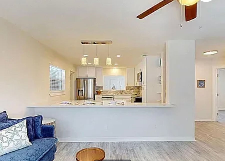 Kitchen peninsula with bar top seating area, pendant lighting, and open view into the living room
