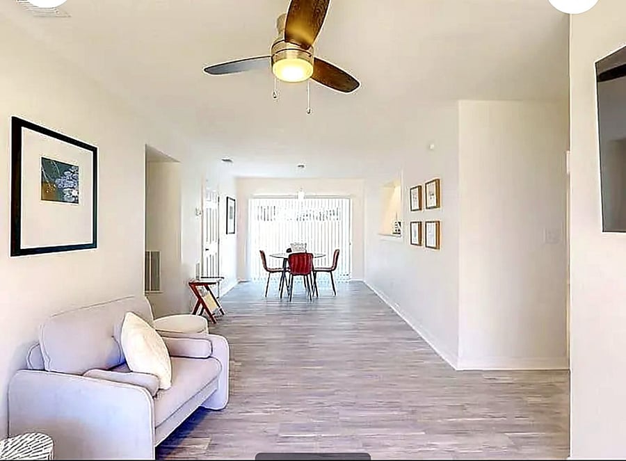 Spacious common area flowing from living room to dining space with backyard access via sliding glass door