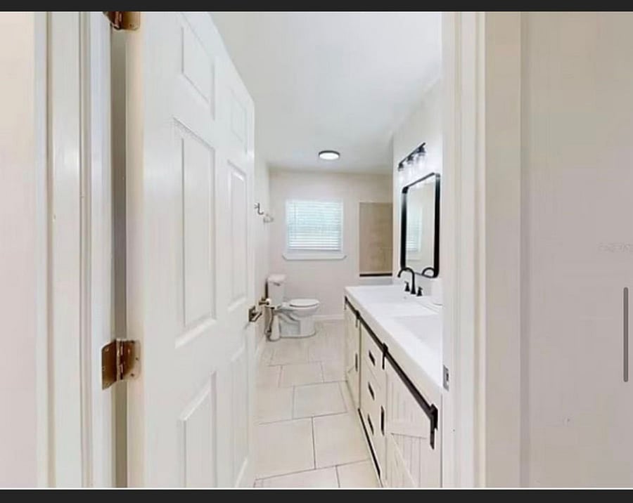 Newly updated full bathroom with modern black fixtures, white vanity, tile flooring, and natural light