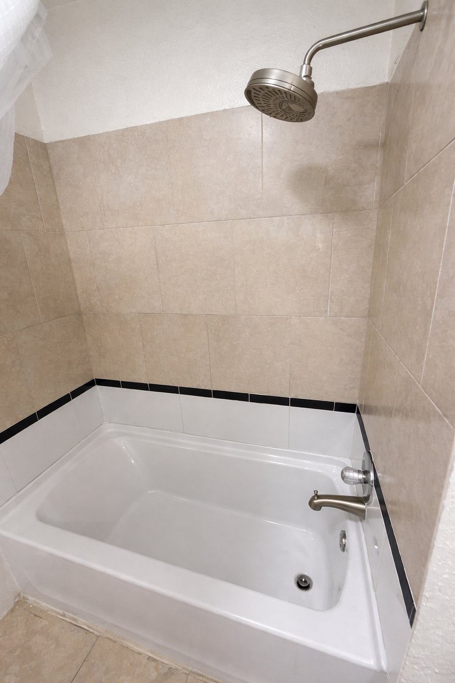 Full bathtub with tiled shower surround for a refreshing experience.