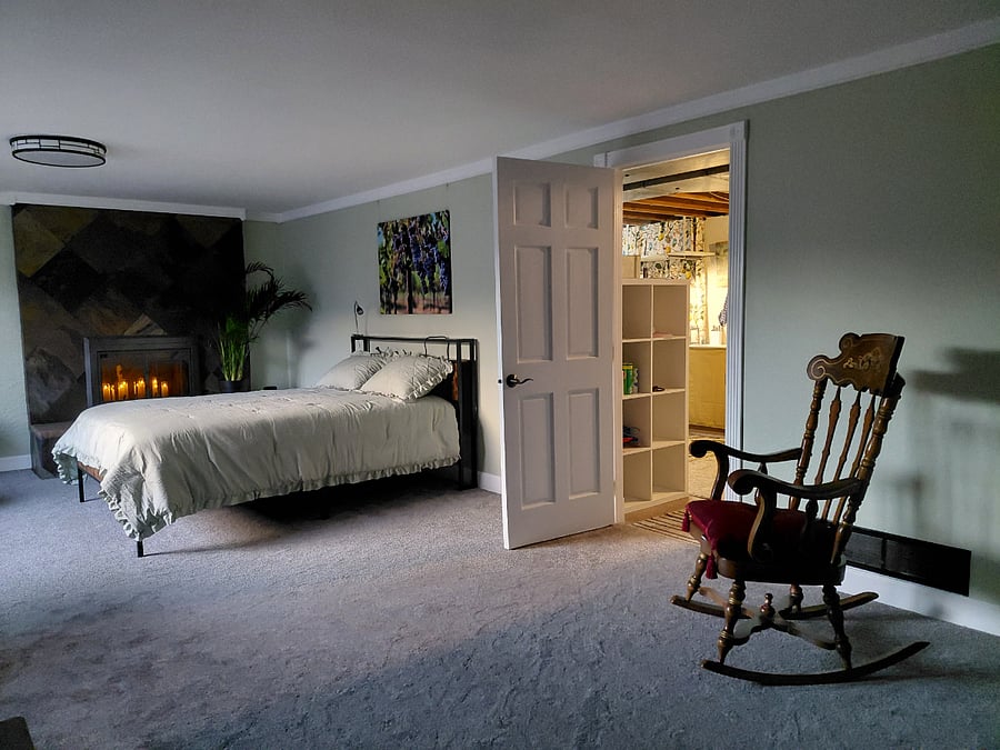 new queen bed; door into second room with kitchenette, shared laundry, and clothing shelves and hanging rack