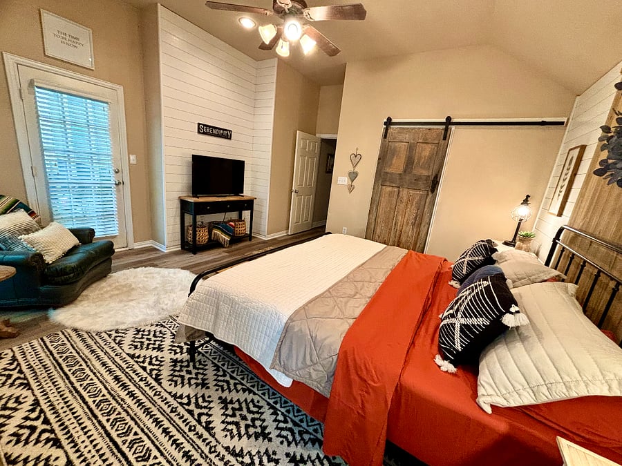Master bedroom with seating, tv and entry into en suite bathroom