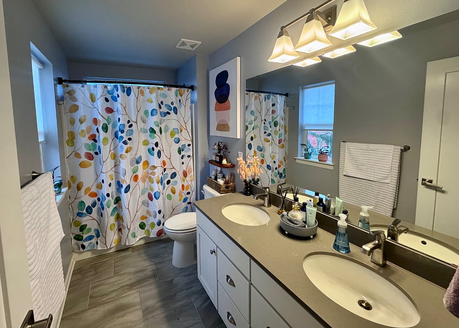 Bathroom with dual sinks and tub with shower.