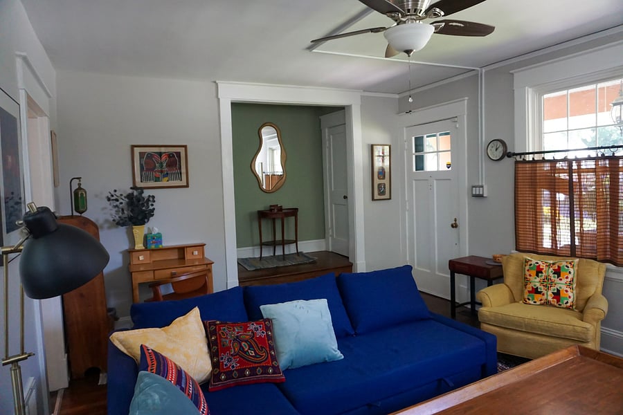 Living room, blue couch has a trundle that pulls out to full size or 2 small beds, blankets, a pillow, towels and sheets are stored in the long end.