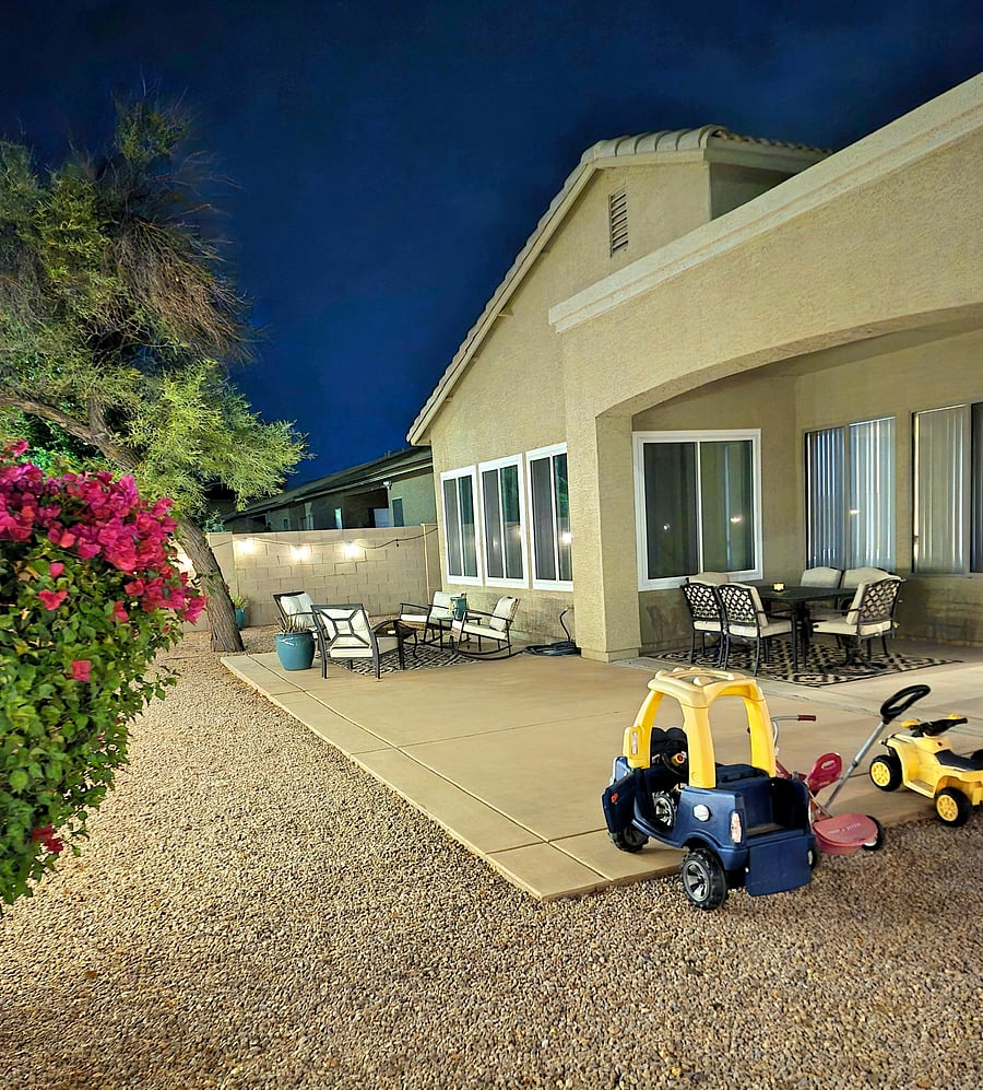 Backyard is fenced in, includes outdoor toys for the littlest, a charcoal grill, patio seating, and covered dining table seating.