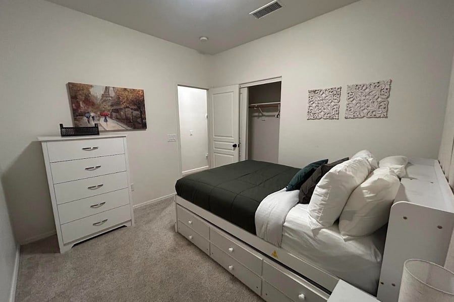 3rd bedroom with full size bed, optional twin trundle bed, closet, dresser, black out curtains, and mounted SmartTV.