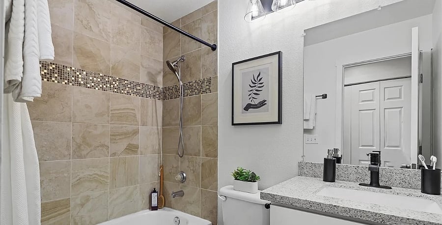 Two bathrooms with tile tub/shower, quartz countertops, and single sinks.