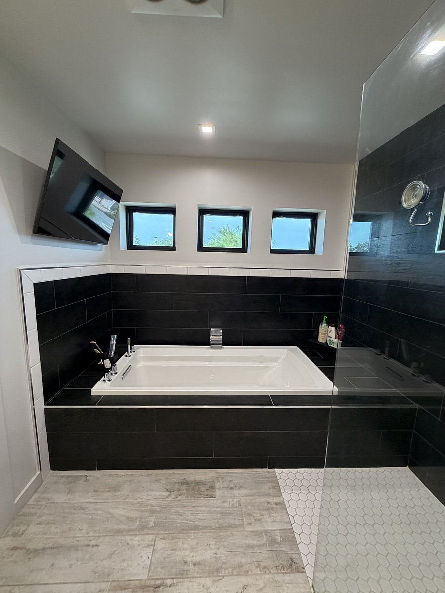 Six foot soaking tub with handheld sprayer and waterfall feature.