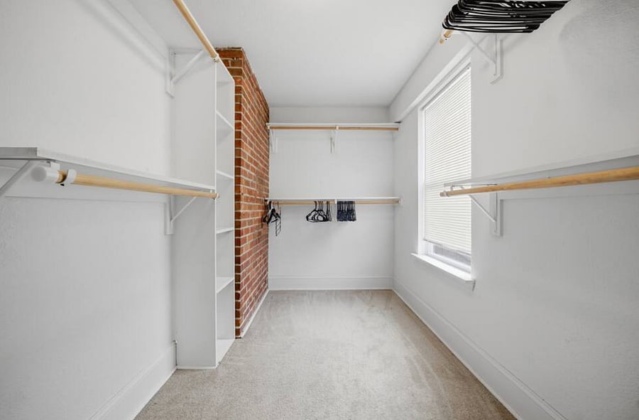 A huge walk-in closet with exposed brick accents.