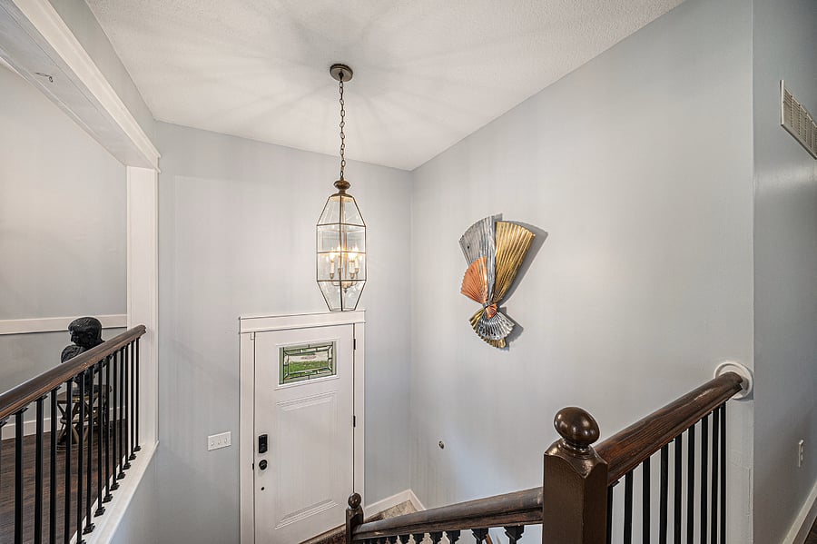 Step through the entry door to a staircase leading up to the living room, with stylish wall dcor adding charm and guiding you into a warm, inviting space above.