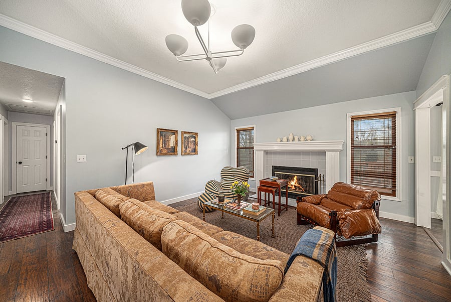 A spacious, stylish lounge with a fireplace, comfy sofa, and unique chairsideal for settling in and enjoying the cozy ambiance.