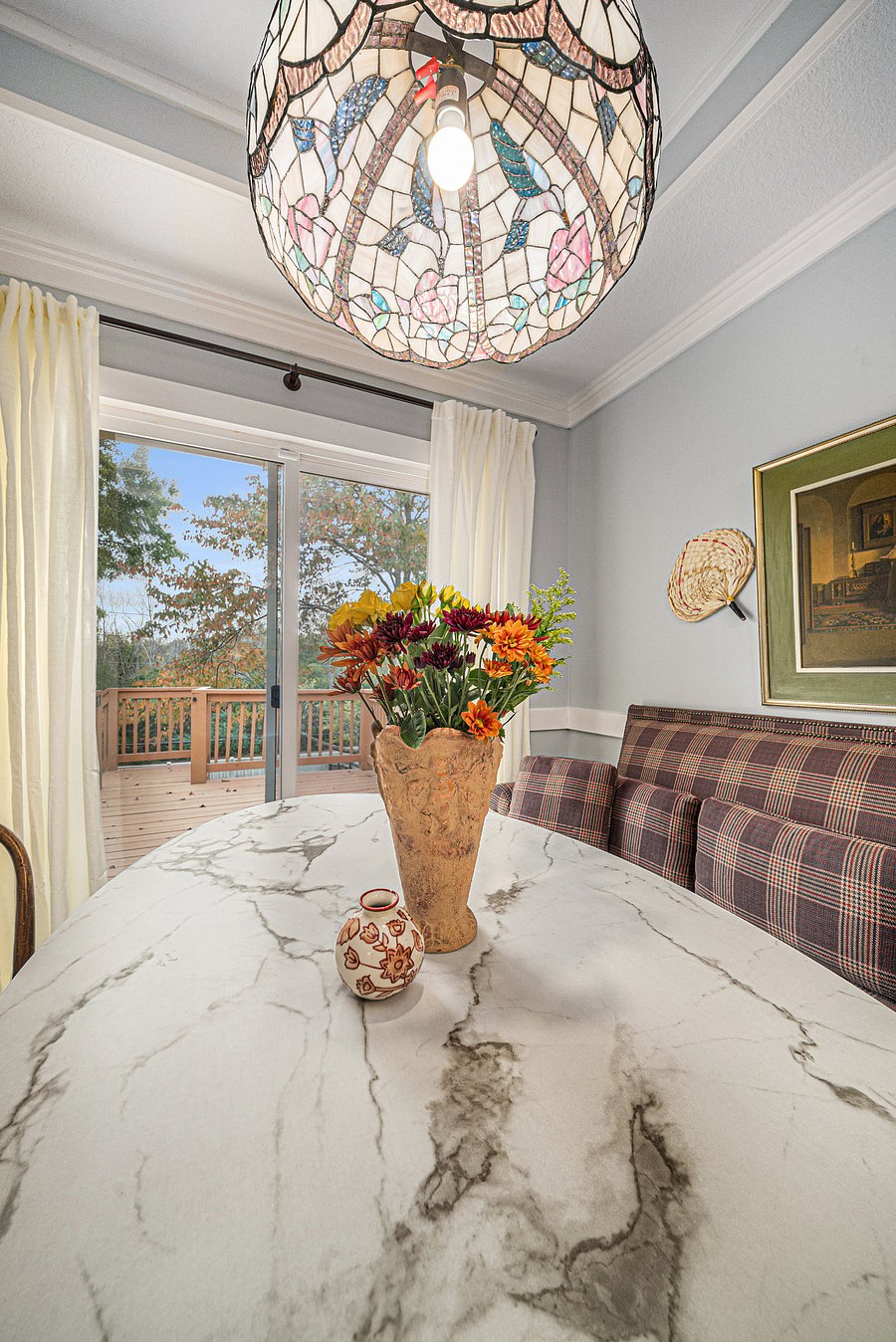 Charming corner with a wooden round table and decorative flower vase, bathed in natural light from the window perfect for relaxing or enjoying a quiet moment.