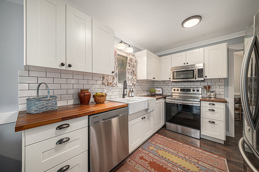 A bright, sunlit kitchen featuring a dishwasher, stovetop with oven, microwave, and sinkbeautifully illuminated by natural light that fills the space and makes cooking and gathering feel warm and inviting.