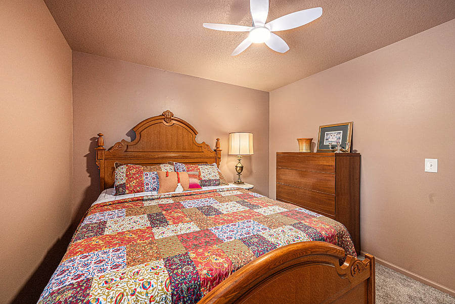 Relax in a cozy bedroom thoughtfully arranged for two, featuring essential furnishings like a side table, lamp, and cabinet for everyday comfort.