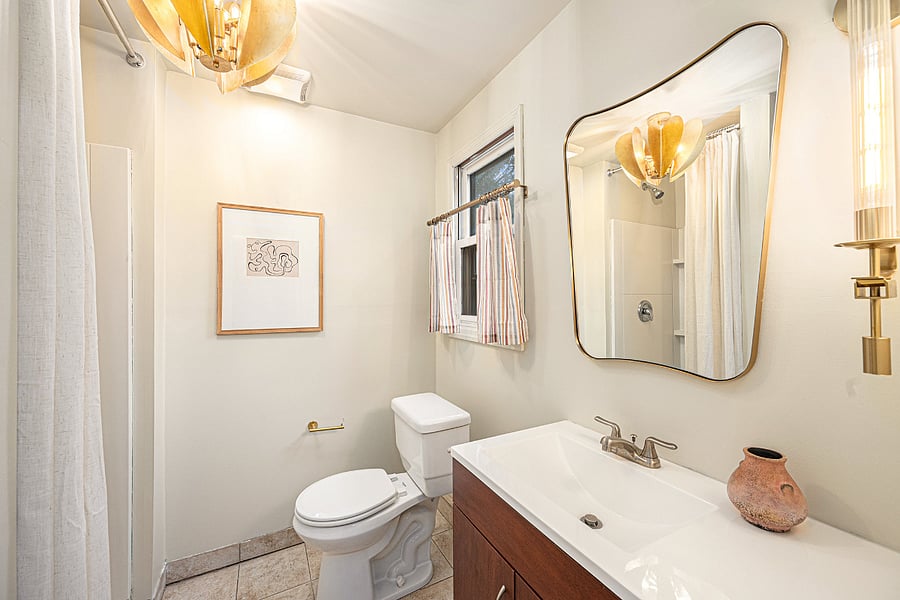 Refresh in this clean, all-white bathroom featuring a shower, toilet, and sink with a vanity mirror, offering a neat and comfortable space for your daily routine.