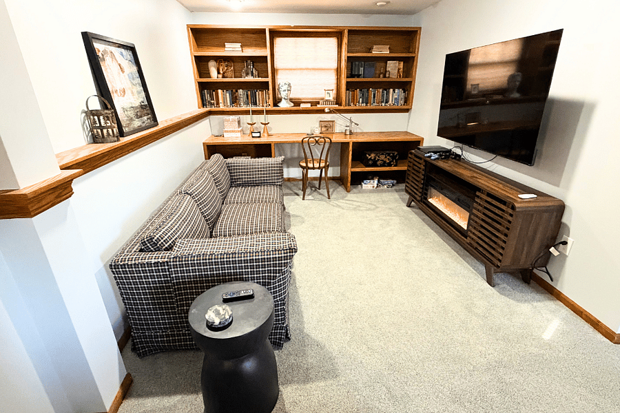 A cozy family room perfect for togetherness, featuring a long couch with side tables, a TV, and a PS4ideal for relaxing, playing games, and making memories with everyone.