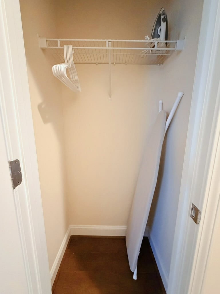 Coat closet w/ hangers, ironing board and iron.