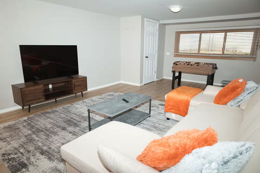 Furnished basement with Smart TV, sleeper couch and game area.