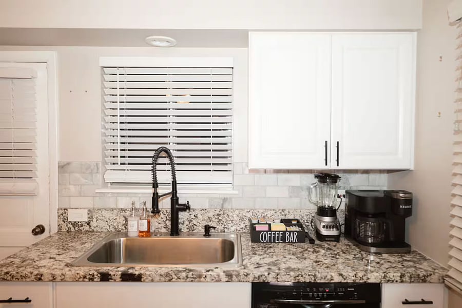 Kitchen with a stove, oven, refrigerator, freezer, dishwasher, toaster, blender, and hot water kettle, cooking basics, baking sheets, dishes, silverware, wine glasses, and a coffee maker with coffee.