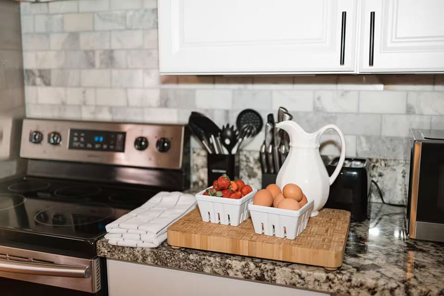 Kitchen with a stove, oven, refrigerator, freezer, dishwasher, toaster, blender, and hot water kettle, cooking basics, baking sheets, dishes, silverware, wine glasses, and a coffee maker with coffee.