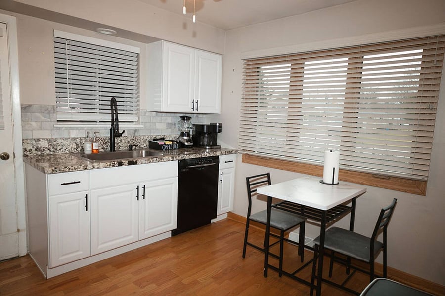 Kitchen with a stove, oven, refrigerator, freezer, dishwasher, toaster, blender, and hot water kettle, cooking basics, baking sheets, dishes, silverware, wine glasses, and a coffee maker with coffee.