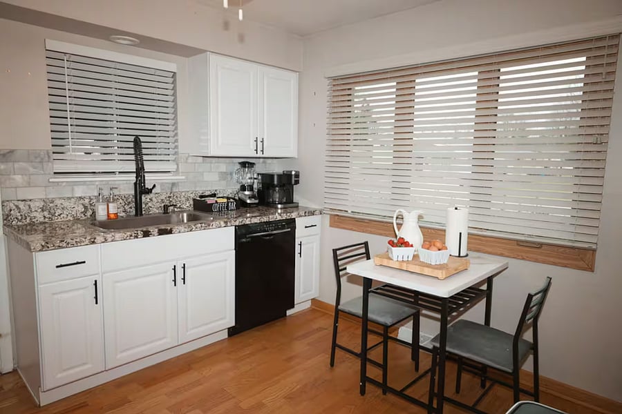 Kitchen with a stove, oven, refrigerator, freezer, dishwasher, toaster, blender, and hot water kettle, cooking basics, baking sheets, dishes, silverware, wine glasses, and a coffee maker with coffee.