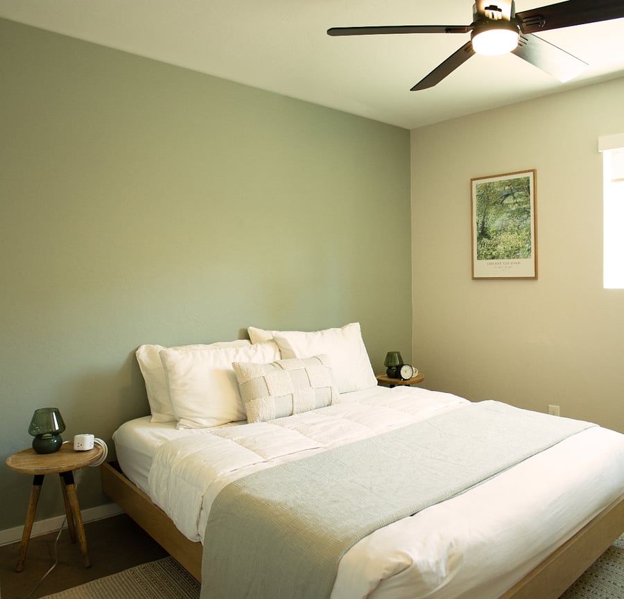 Comfortable bedroom with queen bed, ceiling fan, and ample natural light.