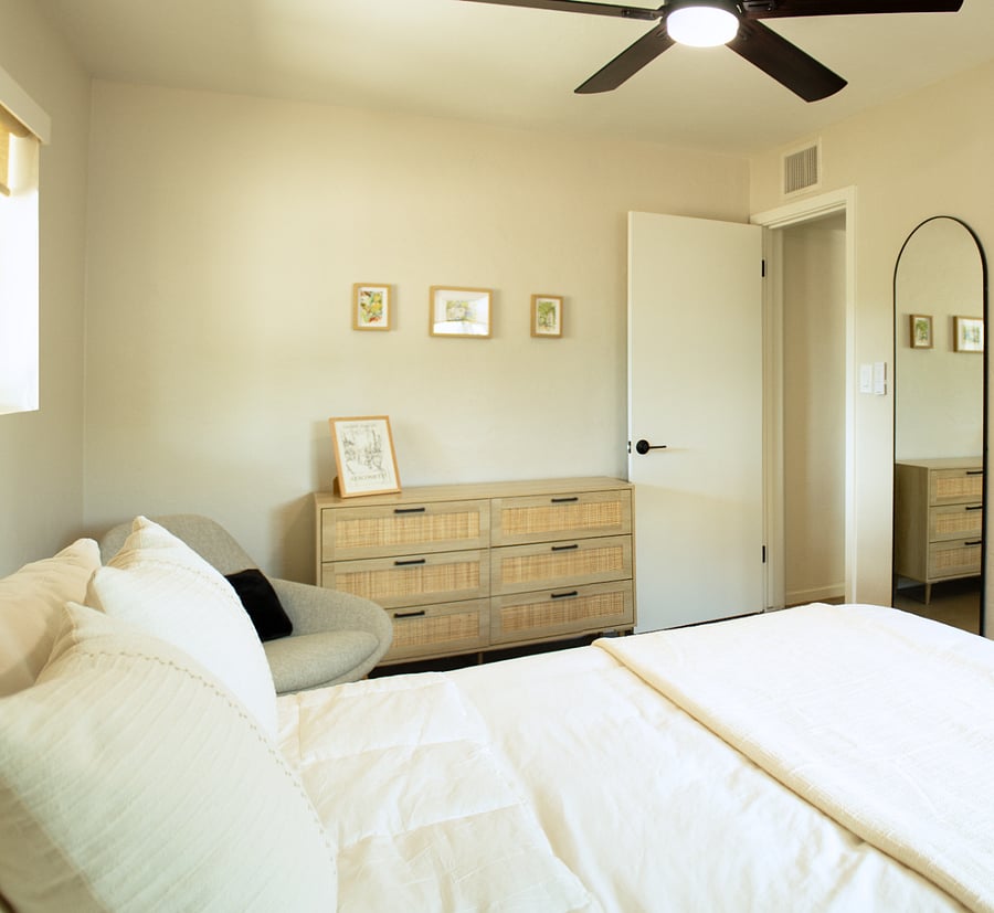 Bedroom with a queen bed, a lounge chair, and ample storage areas.
