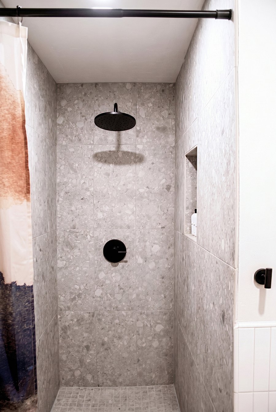 Walk-in shower with terrazzo tile, rainfall head, and built-in niche