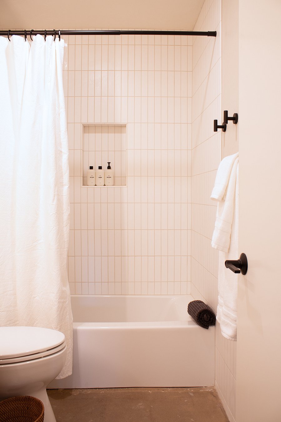 Light-filled bath with tub/shower combo, clean tile, and built-in niche