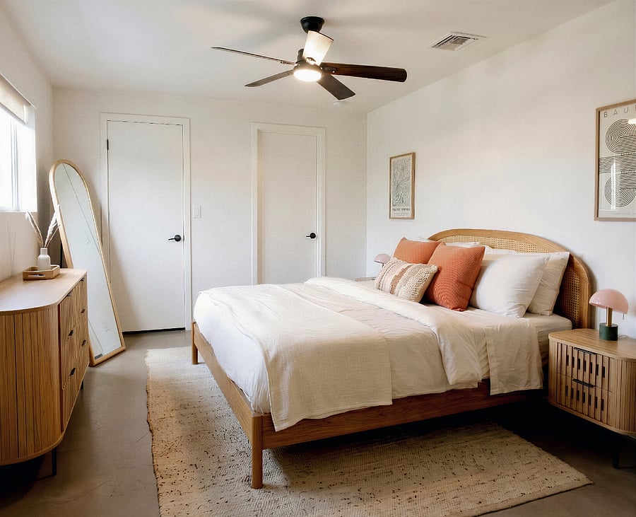 Bright bedroom with king bed, dresser, mirror, and ample storage.