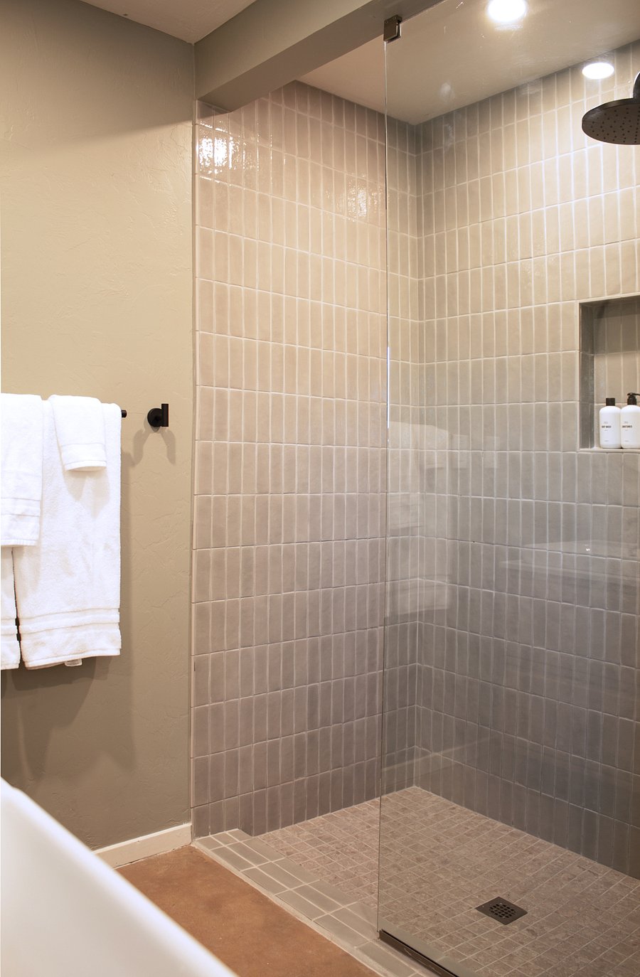 Spa-like walk-in shower featuring custom vertical stack tile, premium matte black fixtures, and a built-in product niche.