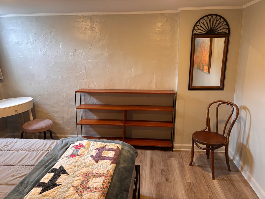 Large bedroom with bookshelf, mirror, and vanity.