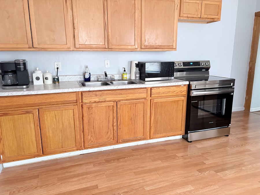 Fully stocked kitchen with new electric range, fridge, and microwave. Amenities include keurig coffee maker, plates, mugs, and silverware.