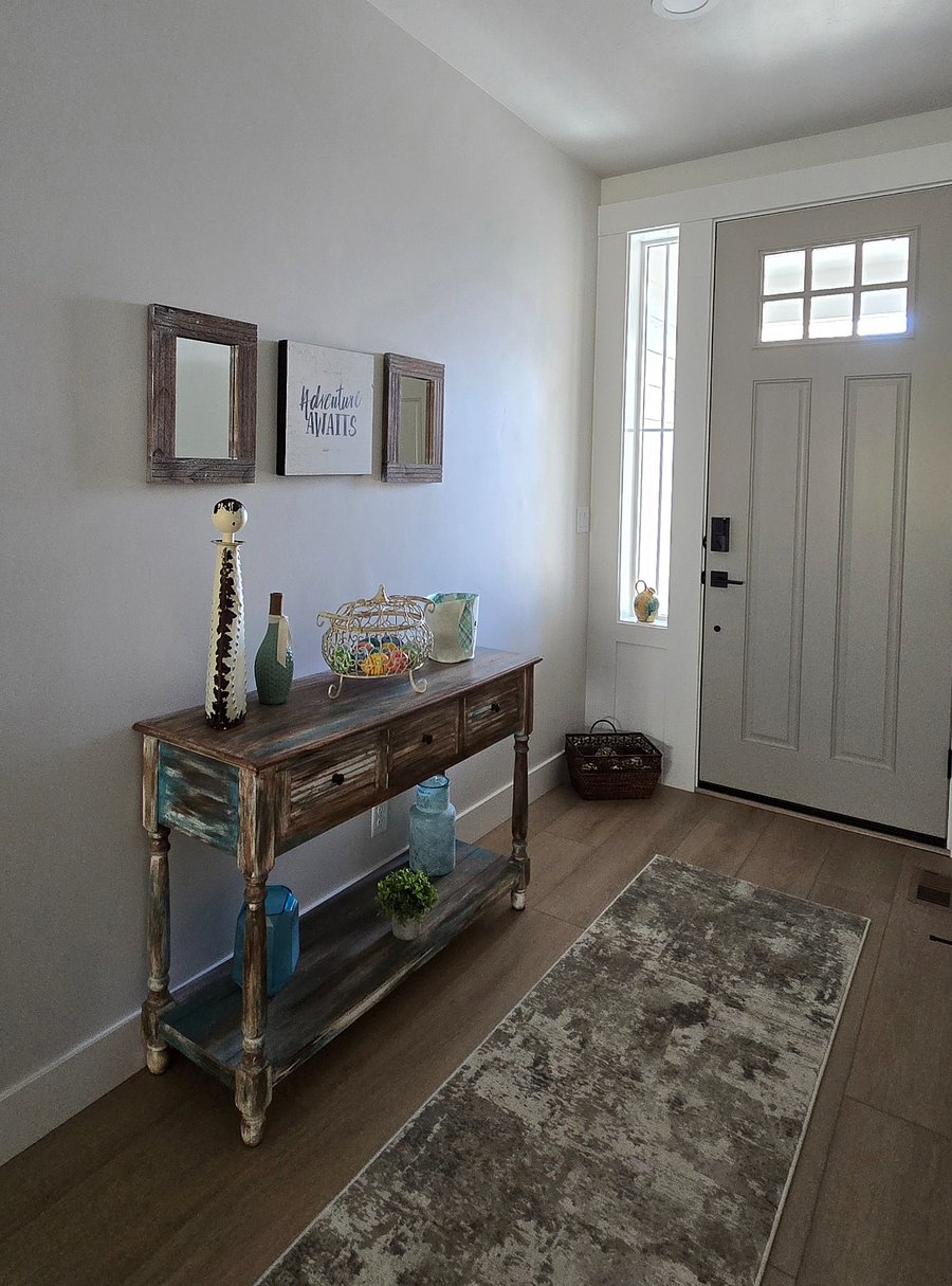 Upon entering the home, you'll be greeted by a charming entryway featuring a stylish table with drawers, complemented by mirrors and tasteful decorations. This thoughtfully decorated space creates a warm and inviting atmosphere, making you feel instantly welcomed and at home as you step inside.