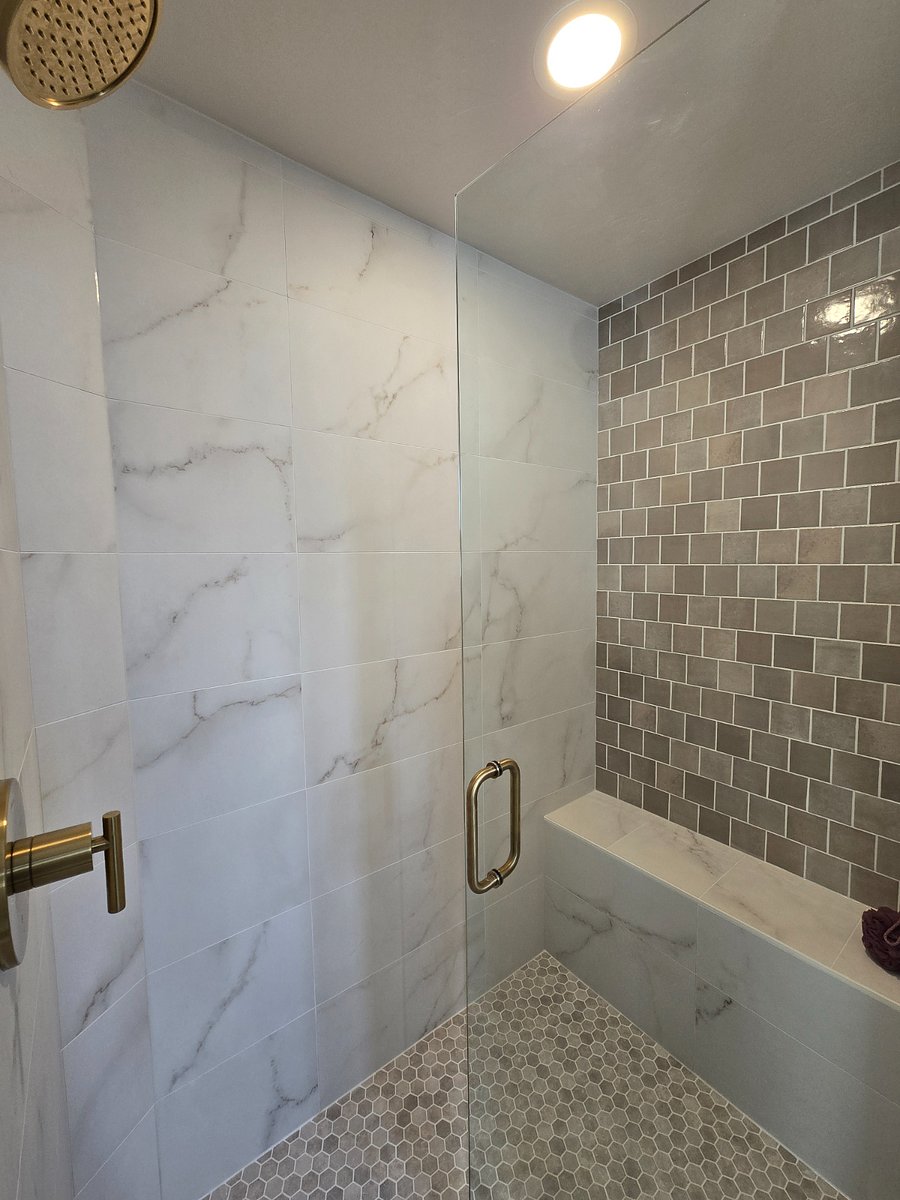 The master shower features a built-in seated bench, complemented by stunning tiled walls and flooring for a luxurious touch.