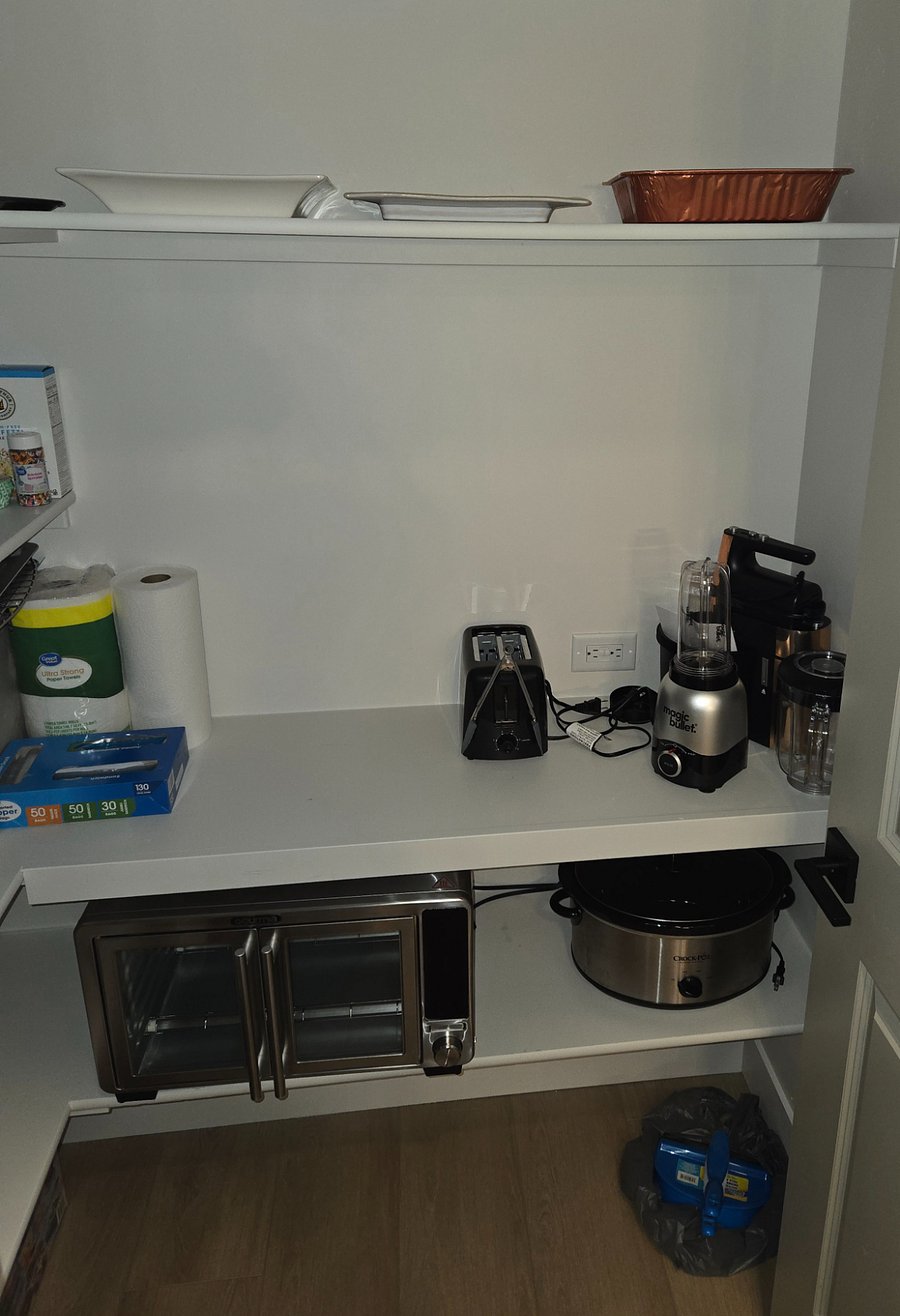 The thoughtfully designed walk-in pantry features multiple shelves and small accessories, along with an outlet for convenient use, providing ample storage and functionality.