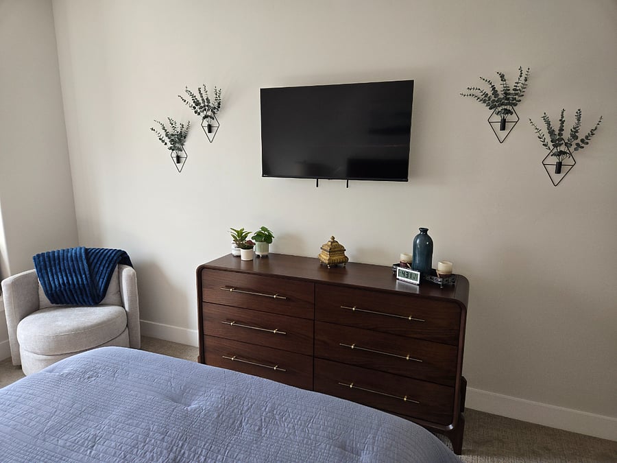 View from the bed showing the dresser with the television and decorative accents, creating a cozy and personalized space.