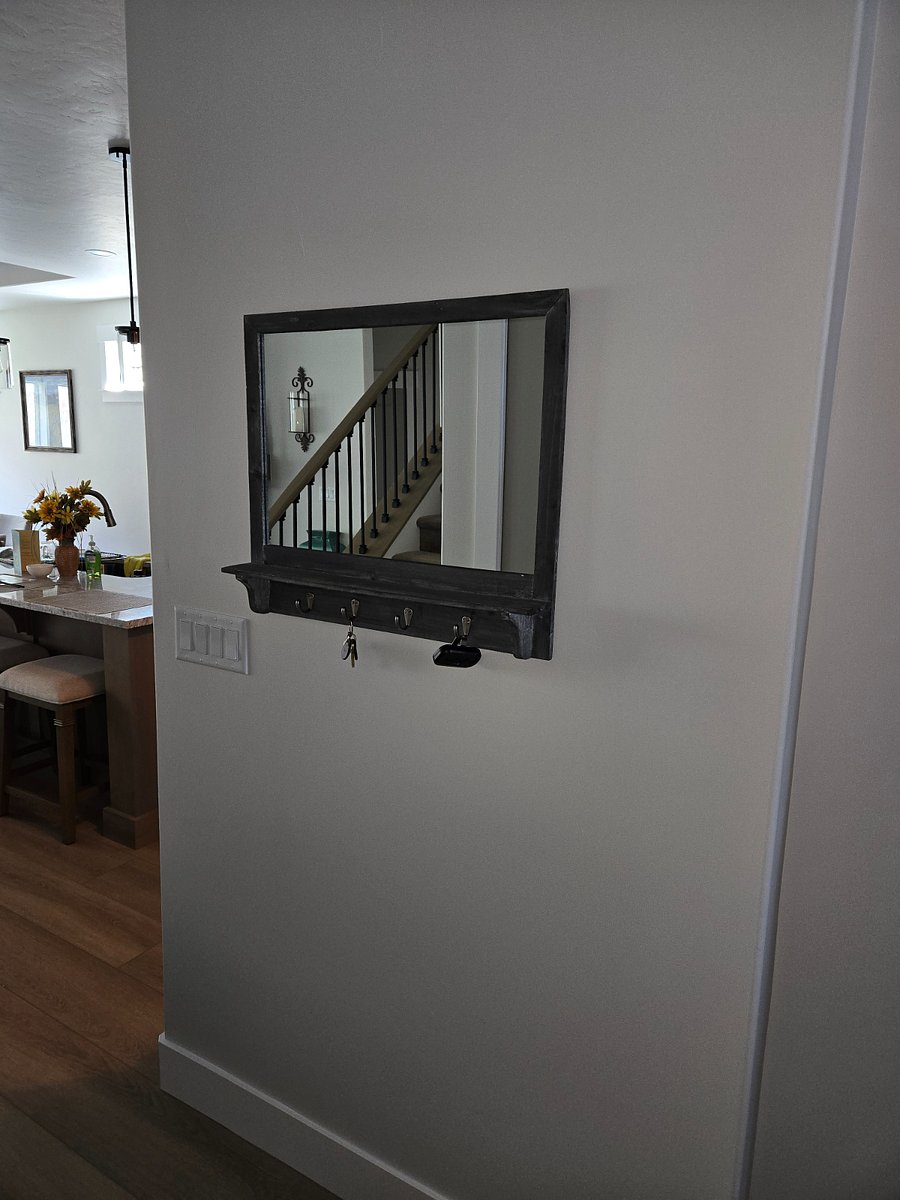 Entryway leading into the kitchen, featuring a key hook with mirror and a glimpse of the breakfast bar area in front of the island. There are three barstools with placemats, providing a comfortable spot to enjoy your coffee or breakfast.