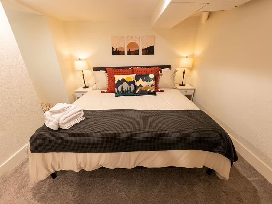 Primary bedroom with a king bed with Colorado mountain art, matching nightstands, and cozy bedding.