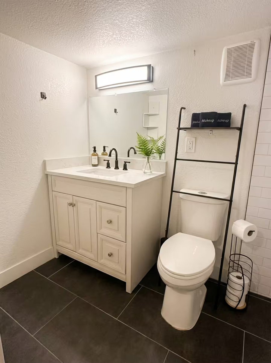 Modern vanity with makeup towels, toiletries, and ladder shelf storage.