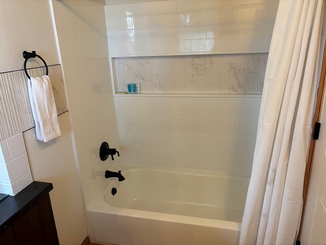 Bathroom - has high ceilings, wood floors, large mirror, bath/shower combo.
