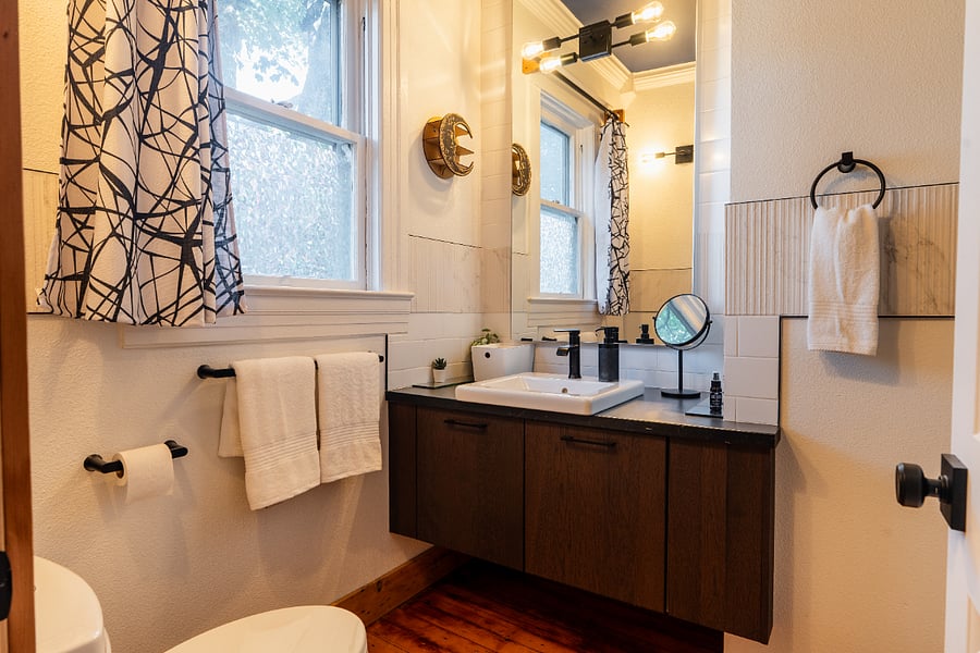 Bathroom - has high ceilings, wood floors, large mirror, bath/shower combo.