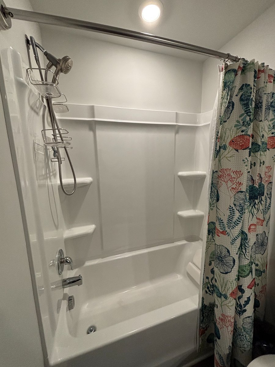 Bathroom with shower, tub, detachable shower head, and storage.